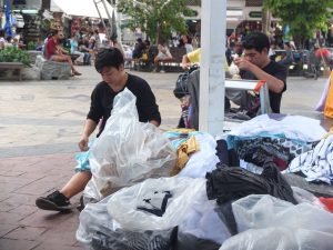 A vendor packs colored clothes into bags and pull out black shirts to display instead Friday at Victory Monument in Bangkok.