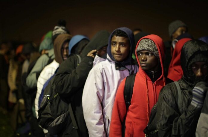 Migrants line-up to register at a processing centre Monday in the makeshift migrant camp known as