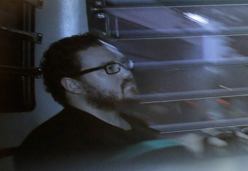 Taken through a tinted glass, Rurik Jutting, a British banker, sitting in a prison bus arrives at a court in 2014 in Hong Kong. Photo: Vincent Yu / Associated Press