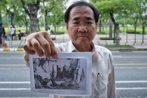 Krisadang Nutcharut holds a photograph of a dead young woman who was sexually assaulted across from where it happened in Bangkok's Sanam Luang adjacent to Thammasat University.