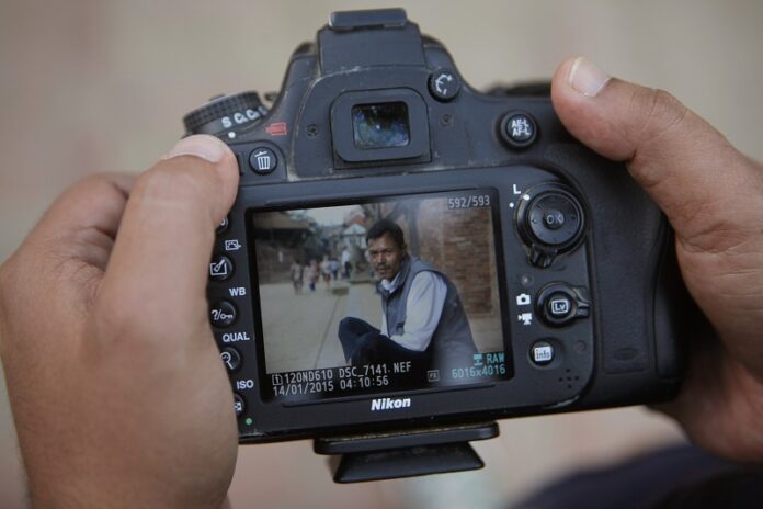Nepalese photographer Jay Poudyal checks photos he took after chatting up different people Oct. 17 in Lalitpur, Nepal. Photo: Niranjan Shrestha / Associated Press