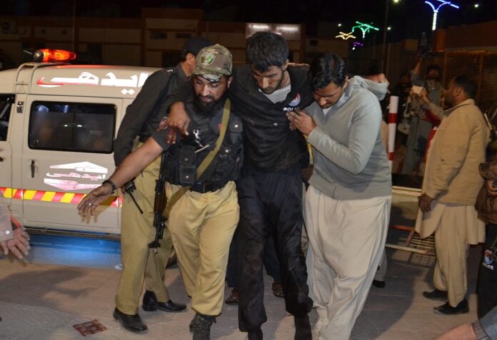 A Pakistani volunteer and a police officer rush an injured person to a hospital on Monday in Quetta, Pakistan after two separate attacks in Pakistan. Photo: Arshad Butt / Associated Press