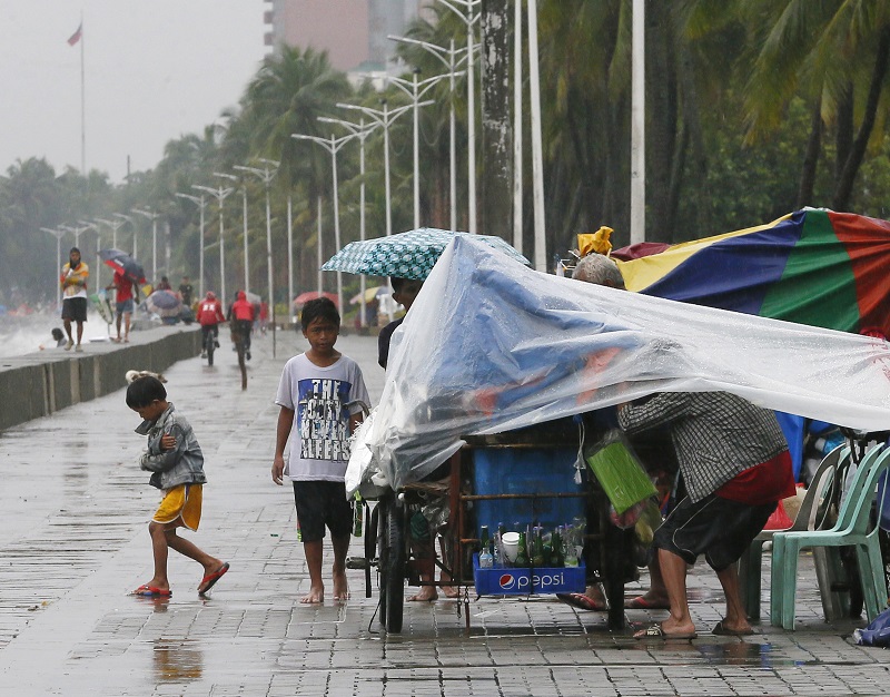 A few residents walk on a promenade under a slight rain brought about by Typhoon