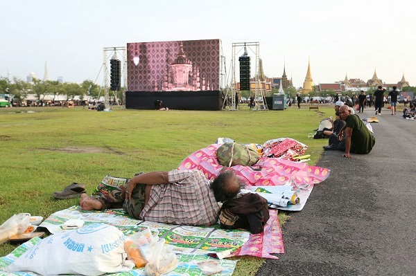 A man sleeps in the Sanam Luang where scenes broadcast from inside the Grand Palace are shown Wednesday in Bangkok.