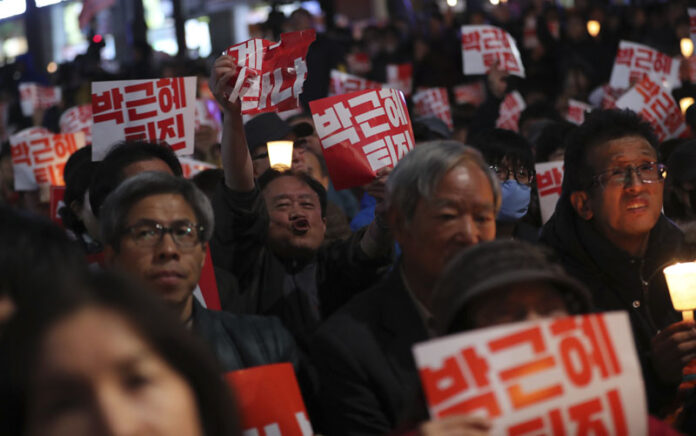 South Koreans hold signs at a rally calling for President Park Geun-hye to step down Saturday in downtown Seoul, South Korea. Photo: Lee Jin-man / Associated Press