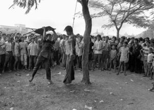 A member of a Thai political faction strikes at the lifeless body of a hanged student outside Thammasat University in Bangkok on Oct. 6, 1976. Photo: Neal Ulevich / Associated Press 