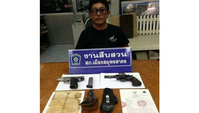 Suchaet Muangsamut is pictured Friday alongside the two guns he displayed in a Facebook video he posted Wednesday, in which he threatened to kill anyone defaming the Late King Bhumibol in Samut Sakhon.