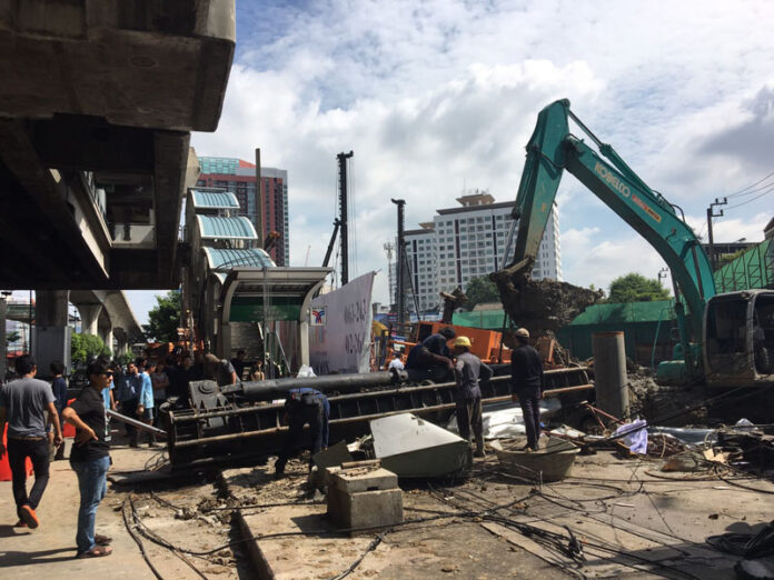Workers remove a fallen crane from across the sidewalk at BTS Phra Khanong on Sukhumvit Road on Sunday in Bangkok.