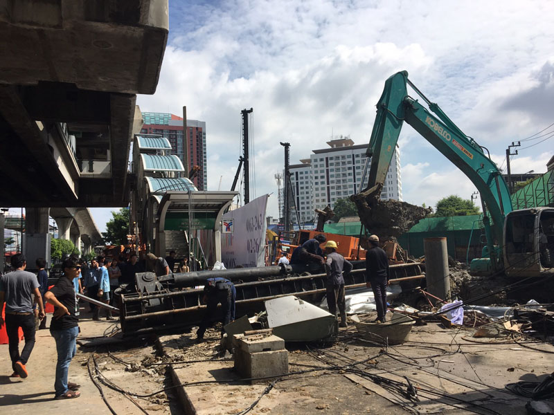 Workers remove a fallen crane from across the sidewalk at BTS Phra Khanong on Sukhumvit Road on Sunday in Bangkok.
