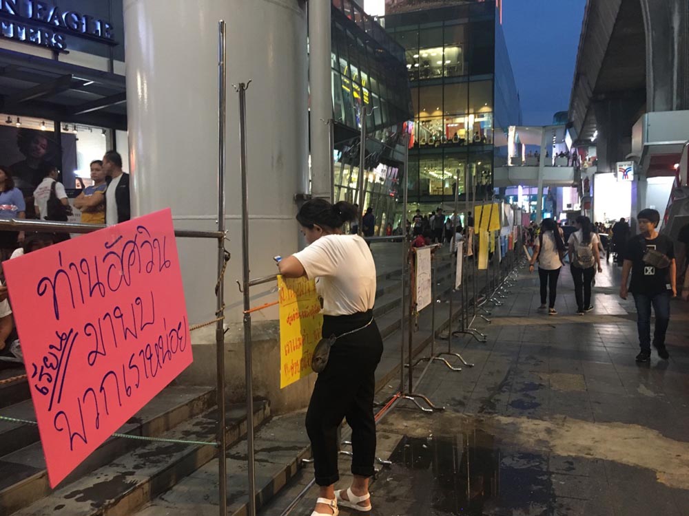 A sign seeking the attention of a specific city official is temporarily set up Wednesday where vendors usually sell goods in front of Siam Square in Bangkok.