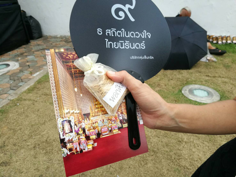 A mourner who made it inside the palace to pay respects to the Late King shows the commemorative items received on Saturday in Bangkok.