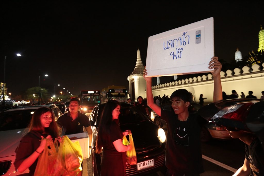 Volunteers on Sunday give out free drinking water to mourners in Bangkok.