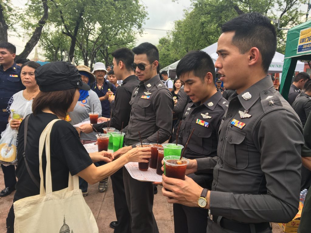 Cadets from the Royal Police Cadet Academy hand out free drinks for mourners Monday at Sanam Luang. 