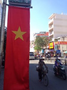 A woman cycles past one of the many banners depicting the Vietnamese flag, Nov. 12 in the streets of Ho Chi Minh City, Vietnam.