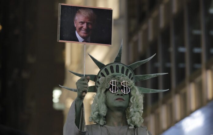 A street performer dressed as the Statue of Liberty holds up a picture of U.S. President-elect Donald Trump Wednesday in Hong Kong's downtown. Photo: Kin Cheung / Associated Press