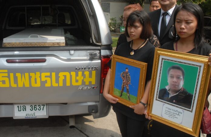 Members of Don Daengchantip’s family hold his portrait next to his coffin on Monday during a protest at a junta complaint center in Bangkok.