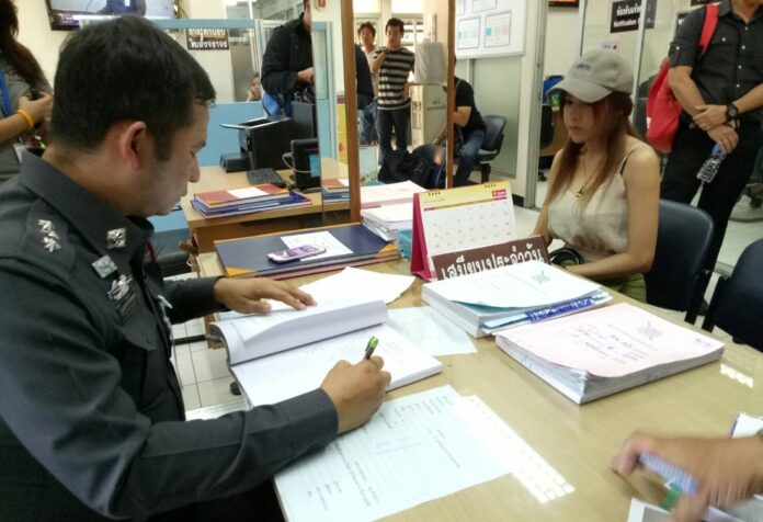 Kritrada ‘Zomy’ Tabtimphol answers questions from a police officer Tuesday at Huai Khwang Police Station in Bangkok.