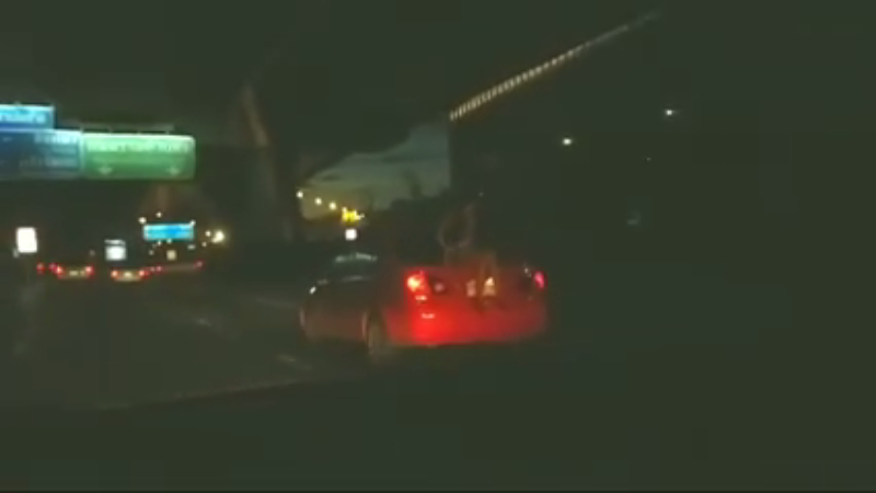 A woman rides on the back of a taxi Sunday night near Suvarnabhumi Airport in a still image taken from a video. Image: Orrawan Phuakthaisong / Facebook