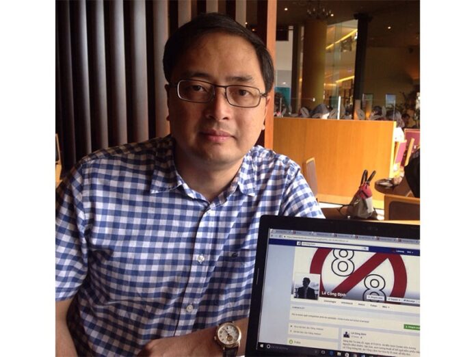 Vietnamese blogger Dinh Cong Le sits next to a laptop with his Facebook profile, displaying a cover image advocating for the dissolution of Article 88, Nov. 12 in Ho Chi Minh City, Vietnam.