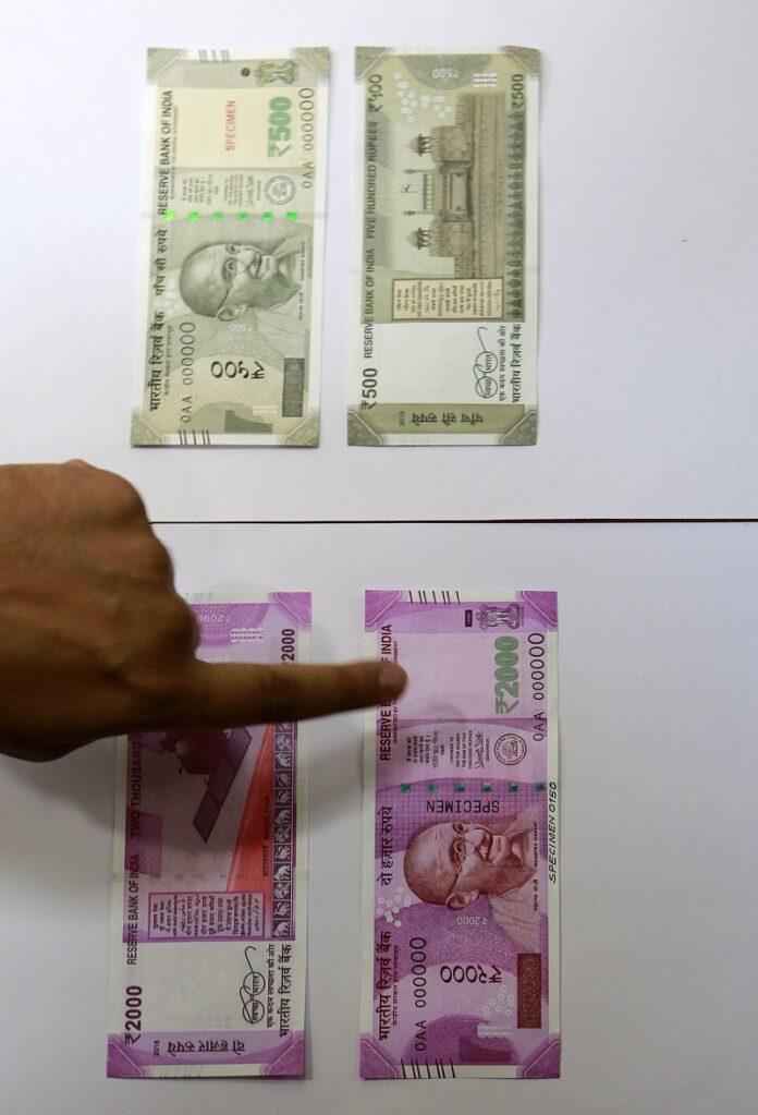 Specimens of the new Indian Rupees 500, top, and 1,000 currency are displayed Wednesday at the Reserve Bank of India headquarters in Mumbai, India. Photo: Rajanish Kakade / Associated Press