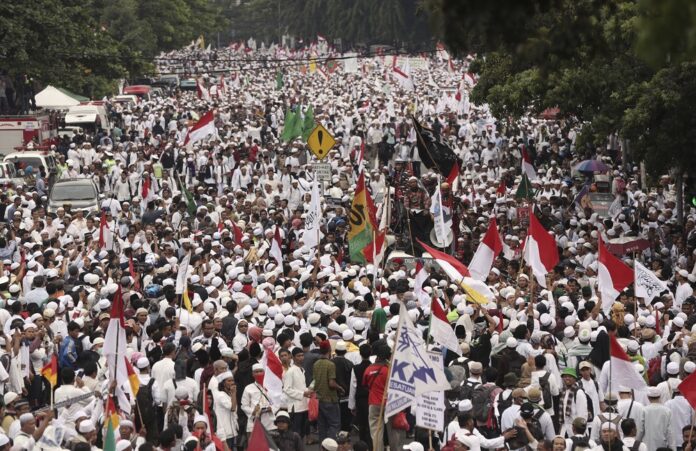 Muslim protesters march Friday during a demonstration in Jakarta, Indonesia. Tens of thousands of hard-line Muslims converged Friday on the center of the Indonesian capital to demand the arrest of its minority-Christian governor for alleged blasphemy. Photo: Achmad Ibrahim / AP