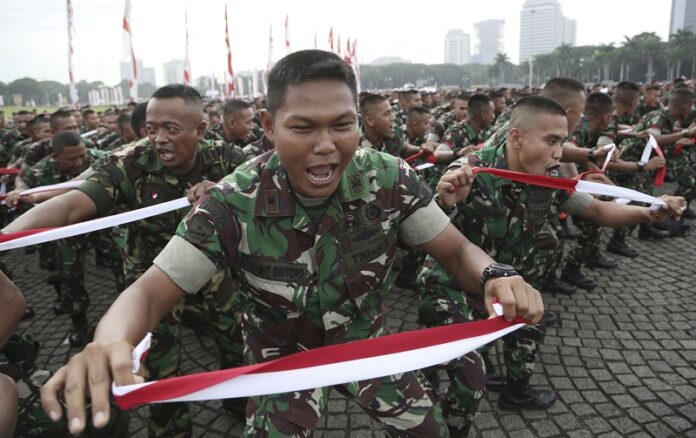 Indonesian soldiers Wednesday perform national-flag-colored headbands during a military-sponsored interfaith rally held ahead of the planned Dec. 2 Muslim protest against Jakarta Governor Basuki Tjahaja Purnama in Jakarta, Indonesia. Photo: Achmad Ibrahim / Associated Press