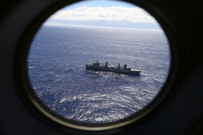 HMAS Success scans the southern Indian Ocean in 2013, near the coast of Western Australia, as a Royal New Zealand Air Force P3 Orion flies over, while searching for missing Malaysia Airlines Flight MH370. Photo: Rob Griffith / Associated Press
