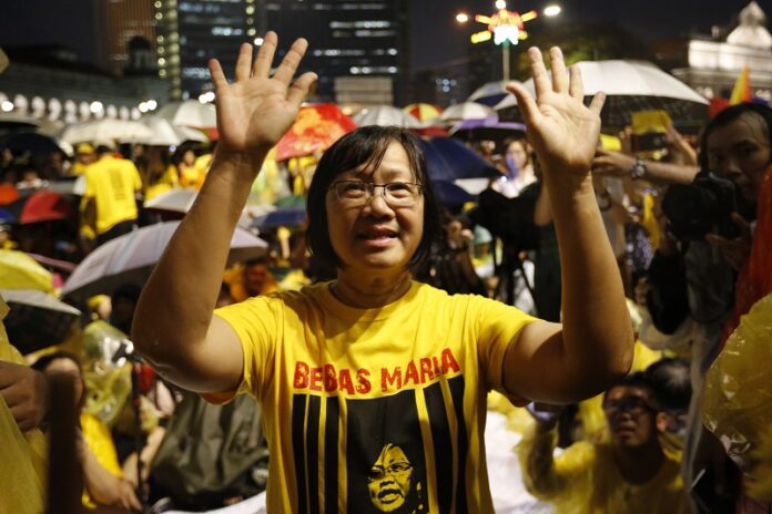 Maria Chin Abdullah, chairwoman of the Coalition for Clean and Fair Elections (Bersih), waves Monday to the crowd during a candlelight vigil at Merdeka (Independence) square in Kuala Lumpur, Malaysia. Photo: Lim Huey Teng / Associated Press