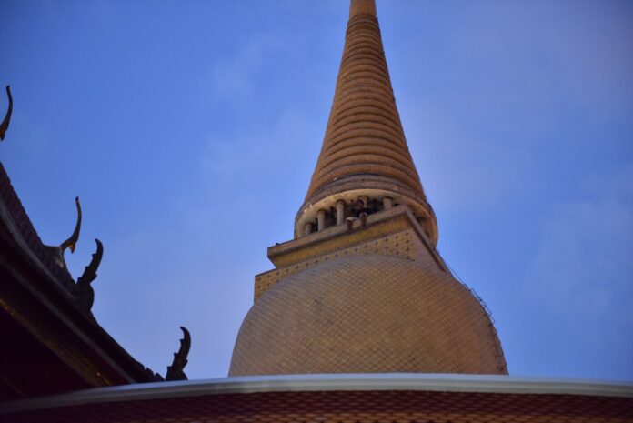 A man sits atop a chedi at Wat Ratchabophit on Monday evening in Bangkok.