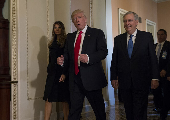 President-elect Donald Trump, accompanied by his wife Melania, and Senate Majority Leader Mitch McConnell of Kentucky, gestures while walking Thursday on Capitol Hill in Washington. Photo: Molly Riley / Associated Press