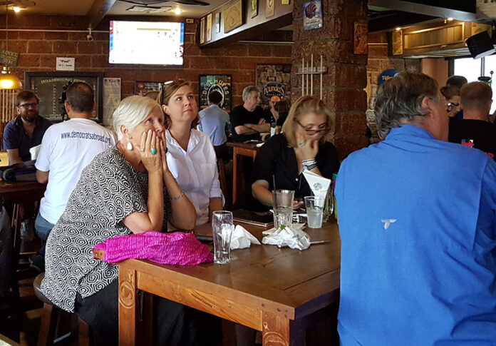 From left, Suzanne Walker, Kirstin Lamoureux and Gudrun Roy watch returns come in from the U.S. general elections on Wednesday morning at Roadhouse Barbecue in Bangkok.