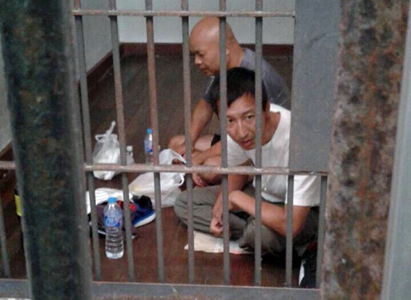 At right, Song Zhiyu, in foreground, and Li Xiaolong seen held in immigration detention after their bid to leave Thailand ended late Tuesday night on a beach in Chumphon.