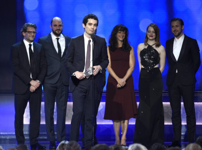 Director Damien Chazelle, center, accepts the award for best picture for