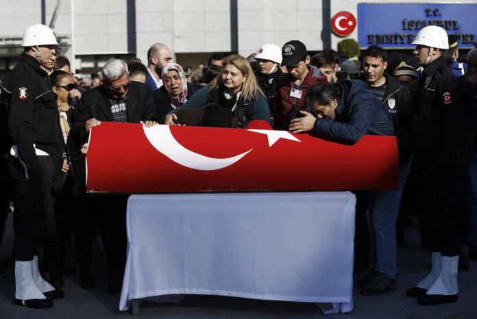 Family members mourn as ministers and colleagues attend a memorial for police officers killed outside the Besiktas football club stadium late Saturday, in Istanbul. Photo: Emrah Gurel / AP.