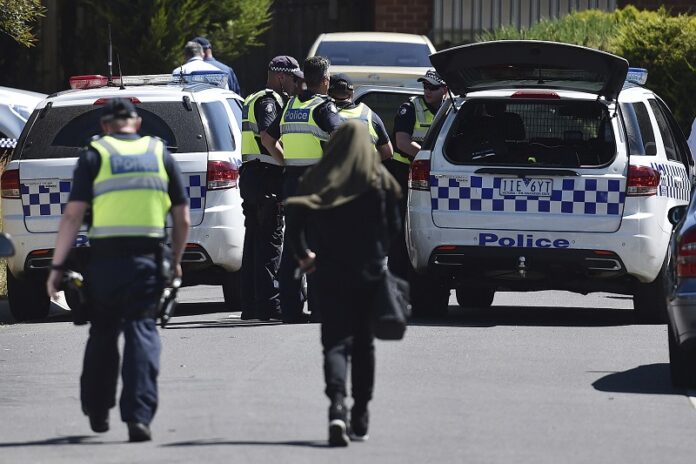 Police accompany a woman as they attend the scene where a house was raided on Friday at Meadow Heights in Melbourne, Australia. Photo: Julian Smith / AAP Image via AP