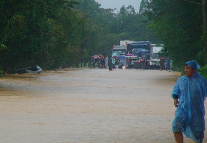 A man wades near a submerged vehicle along a flooded section of Route 41 in Chumphon province on Wednesday morning.