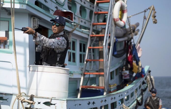 A Thai navy officer on Dec. 9 inspecting a fishing boat in the waters off the coast of Samut Sakhon province.