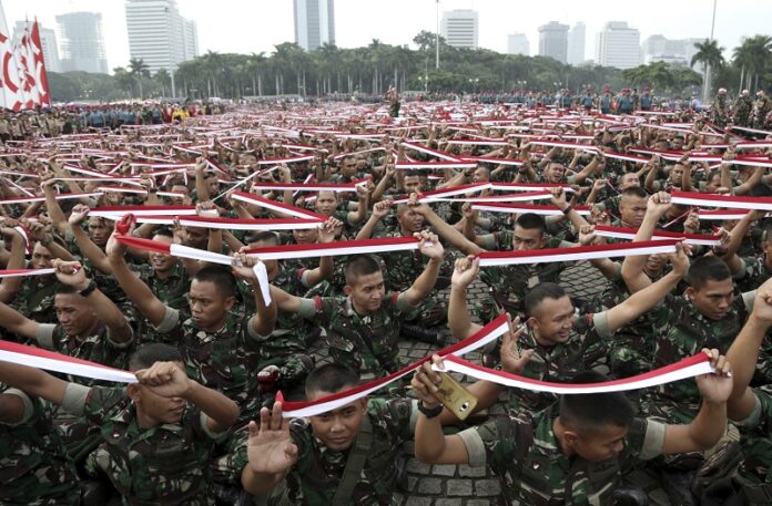Indonesian soldiers hold up headbands Wednesday in the color of the national Red-White flag during a military-sponsored interfaith rally held ahead of the planned Dec. 2 Muslim rally against Jakarta Governor Basuki Tjahaja Purnama in Jakarta, Indonesia. Photo: Achmad Ibrahim / Associated Press
