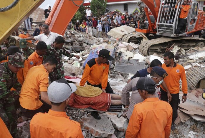 Rescuers recover the body of a victim from the rubble of a collapsed building Wednesday after an earthquake in Pidie Jaya, Aceh province, Indonesia. Photo: Heri Juanda / Associated Press
