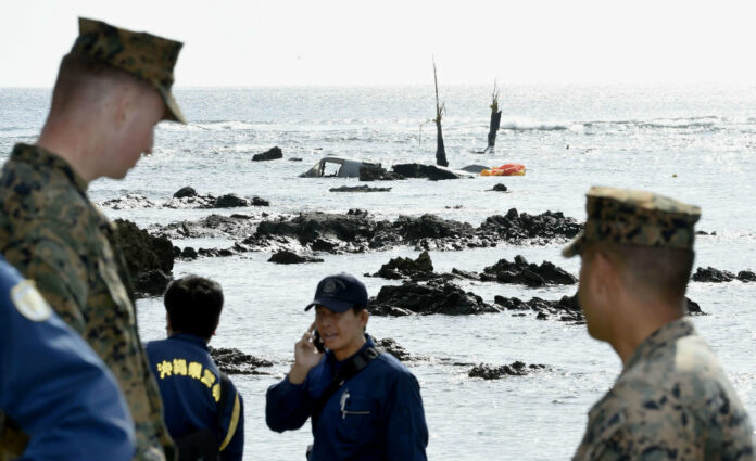 Officers of Okinawa Prefectural Police and U.S. military investigate the site where debris of a U.S. military MV-22 Osprey, background, was spotted in shallow waters off Nago, Okinawa, southern Japan, Dec. 14, 2016, after its crash-landing. Photo: Takumi Sato/ AP.