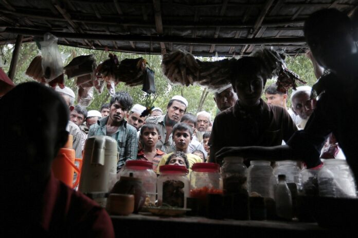 Rohingya from Myanmar, watch a television program about them being played on a mobile phone inside a tea stall, at an unregistered refugee camp in Teknaf, near Cox's Bazar, a southern coastal district about, 296 kilometers (183 miles) south of Dhaka, Bangladesh. Photo: A.M. Ahad / Associated Press