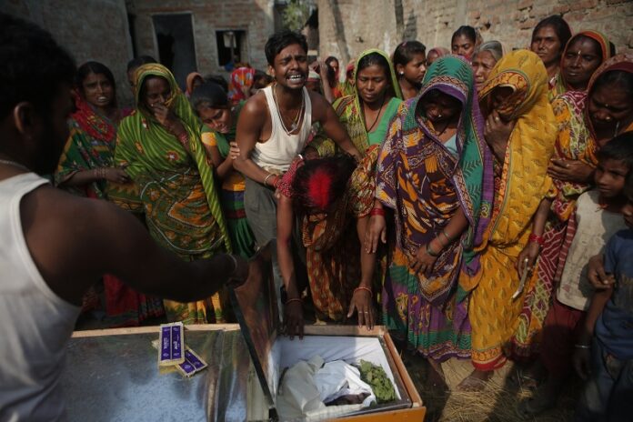 Saro Kumari Mandal, 26, cries in November as she leans on the coffin carrying her husband Balkisun Mandal Khatwe, 26, a migrant worker who died in his sleep in Qatar, at Belhi village, in Saptari district, Nepal. Photo: Niranjan Shrestha / Associated Press