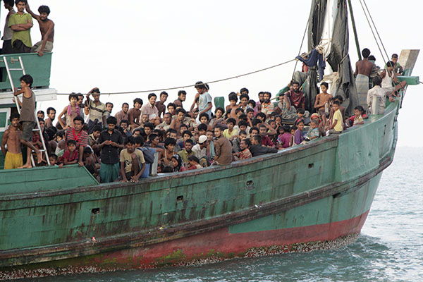 Migrants including Myanmar Rohingya Muslims sit on a boat as they wait to be rescued by Aceh fishermen May 20, 2015, in the sea off East Aceh, Indonesia, after being pushed back to sea by Thailand. Photo: S. Yulinnas / Associated Press