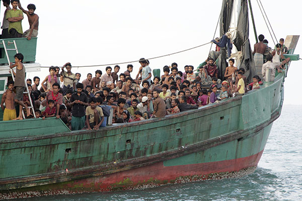 Migrants including Myanmar Rohingya Muslims sit on a boat as they wait to be rescued by Aceh fishermen May 20, 2015, in the sea off East Aceh, Indonesia, after being pushed back to sea by Thailand. Photo: S. Yulinnas / Associated Press