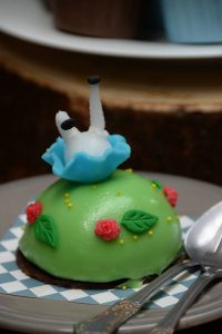 Green Tea Bush (190 baht) is a dense, dome-shaped mousse with a sponge cake base and slight green tea flavor, topped with sugar roses and Alice’s skirt, bloomers and legs made of fondant, depicting her falling into shrubbery.