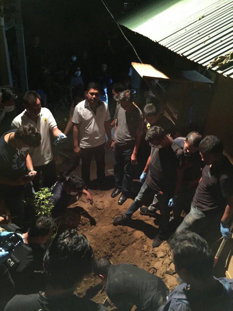 Officers exhume what they believe to be the body of murder victim Suphaksorn Pontaisong on Wednesday evening in Kanchanaburi province.