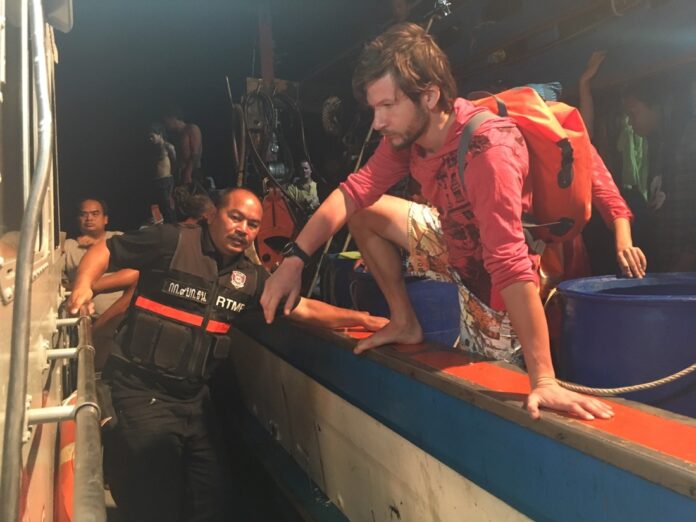 Tourists who survived the sinking of their diving boat disembark Monday night on the shore of Satun province.