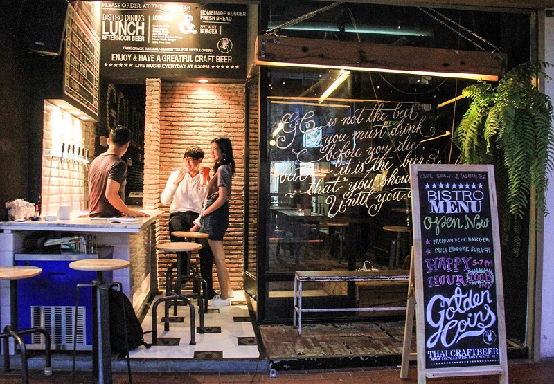 Pipattanaphon ‘Pieak’ Poompho, at left, with his customers at Goldencoins Taproom.