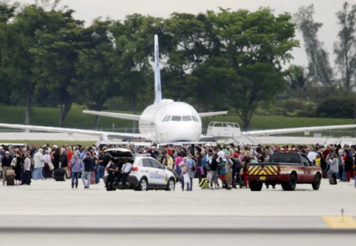 People stand on the tarmac Friday at the Fort Lauderdale-Hollywood International Airport after a shooter opened fire inside a terminal of the airport, killing several people and wounding others before being taken into custody in Fort Lauderdale, Florida. Photo: Lynne Sladky / Associated Press