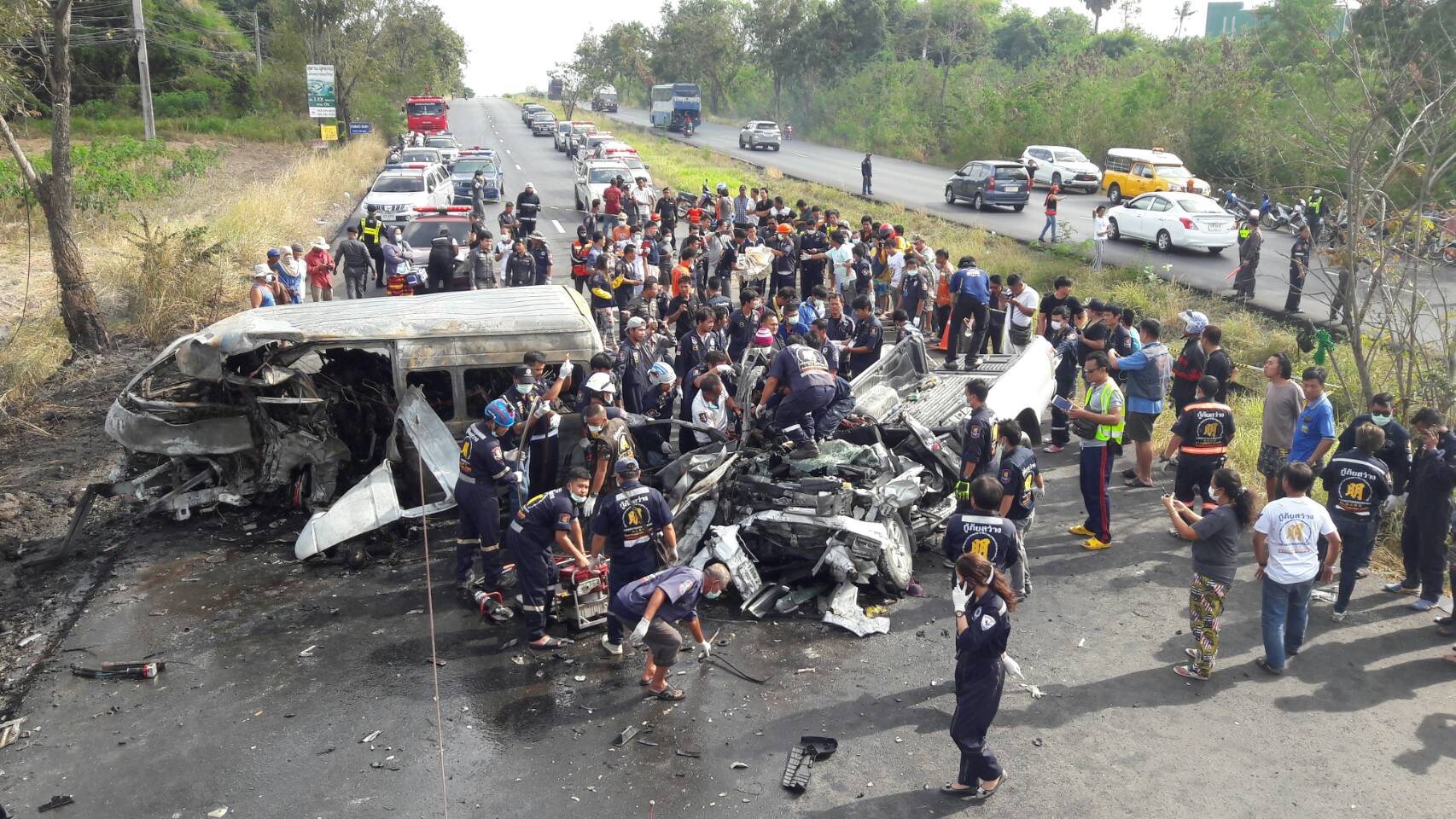Policemen and rescue officials on the scene of a Monday afternoon crash in Chonburi where 23 died when a van collided with a truck. 